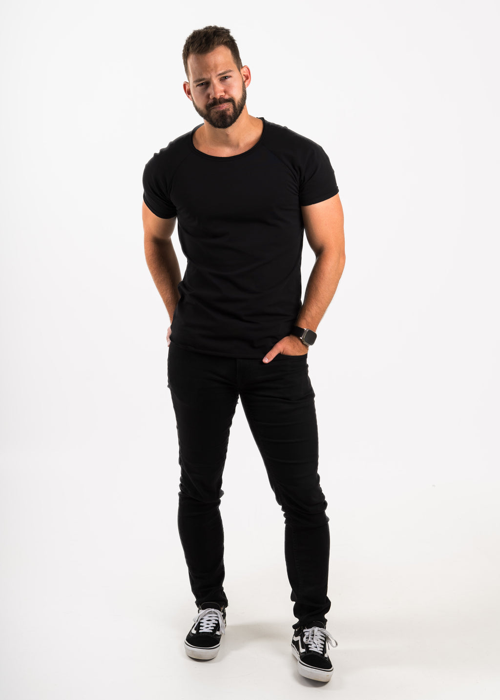 Man wearing a tailored Norloom black t-shirt and black jeans on a white background