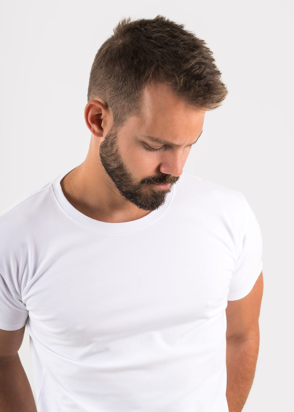 Man wearing a plain white t-shirt against a light gray background